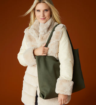 Women model wearing faux fur jacket with green tote handbag.