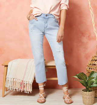 Model wearing light denim jeans with raw hem bottom.