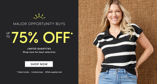 Woman in black and white striped shirt and blue jeans standing next to a promotional banner for a up to 75% off sale.