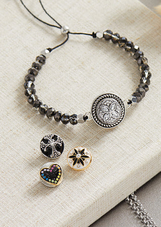 Adjustable gray colored beaded bracelet and four snap charms.