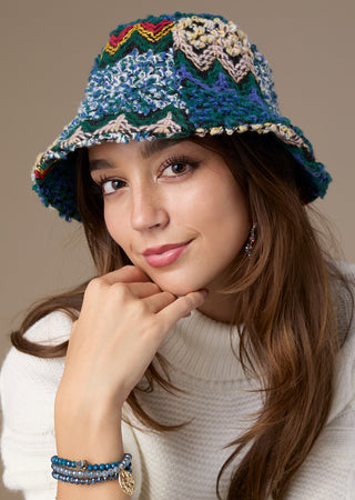 Model wearing multicolored hat on beige background.