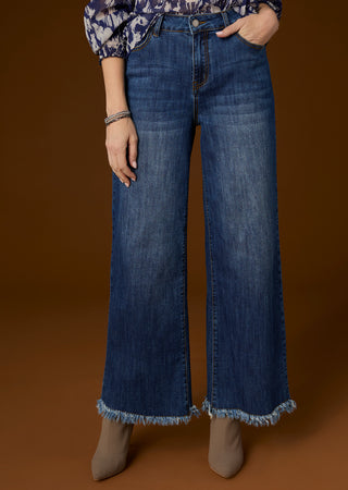 Model on brown background wearing dark denim wide leg jeans