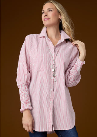 Model on brown background wearing pink long sleeve shirt