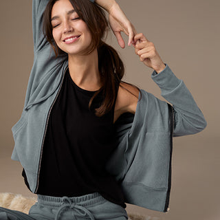 Woman wearing a gray cardigan over a black top on a brown background