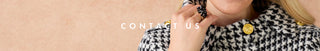 A close-up lifestyle shot of a model wearing a black and white houndstooth knit jacket with gold buttons, touching their face against a soft beige background. White text overlay reads 'CONTACT US'.