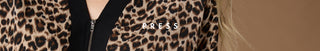 Close-up of a leopard-print zippered garment with a black center panel and a white 'PRESS' watermark across the chest.