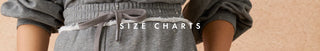 A close-up of a person wearing a gray drawstring waist top or dress, with the text 'SIZE CHARTS' overlaid across the center. The background is a soft beige wall.