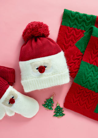 Christmas-themed knitted items including a hat, scarf, and earrings on a pink background