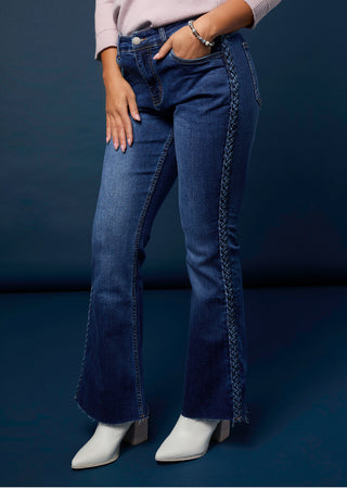 Person wearing blue jeans with a braided design on a dark background