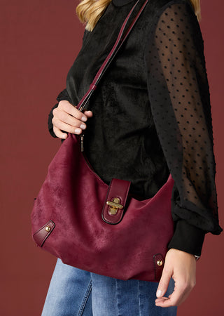 Model wearing maroon handbag and black top.
