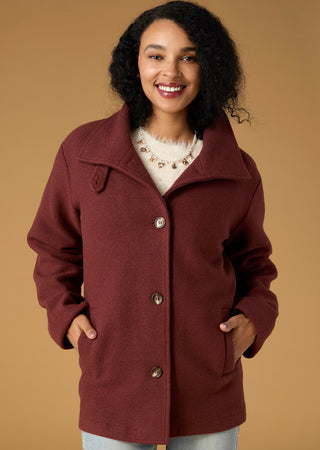 Model wearing burgundy jacket on tan  background.