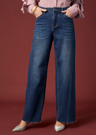 Model wearing blue jeans on maroon background.