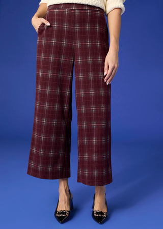 Model wearing plaid pants on blue background.