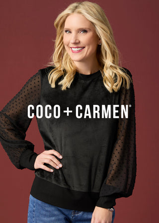 Model wearing a long sleeve black top on maroon backgound.