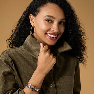Model wearing green top on tan background.
