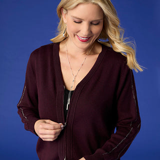 Model wearing burgundy top on bright blue background.