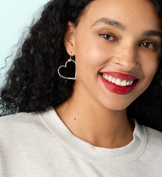 Model wearing silver heart dangle earrings