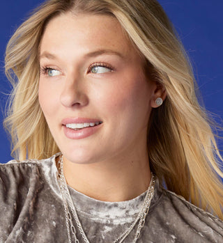 Model wearing silver stud earrings.