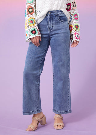Shop denim. Model wearing wide leg blue jeans.
