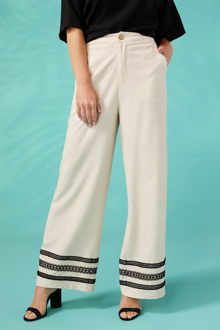 White pants with black trim worn by a person on a teal background