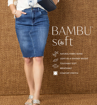 Model wearing a dark denim skirt on a tan textured background promoting 'BAMBU SOFT DENIM' collection. 