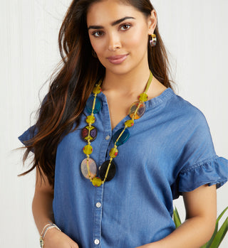 Model wearing a blue top with ruffle short sleeves and multicolored necklace.