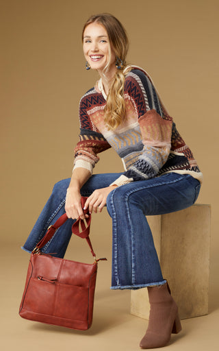 Model wearing dark denim flare jeans and sweater in fall hues.