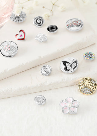 Collection of various silver and gold charms on a white surface with a soft focus background.