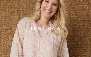 Woman wearing a cream floral top on a brown textured background.